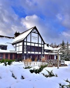 un edificio con nieve en el suelo delante de él en Hotel SPA Dr Irena Eris Wzgórza Dylewskie, en Wysoka Wieś