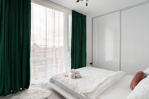 a bedroom with green curtains and a bed with two towels at Elegant Urban Retreat - City Center in Arad