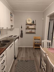 una cucina con armadi bianchi, tavolo e lavandino di Guesthouse Pekkala a Rovaniemi