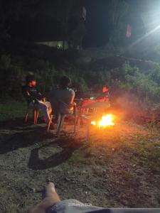 a group of people sitting around a fire at night at Him valley huts and camping in Tehri-Garhwāl