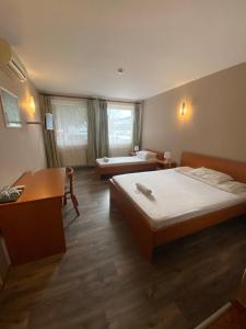 um quarto de hotel com duas camas e uma escrivaninha e uma escrivaninha em Hotel Ferihegy em Vecsés