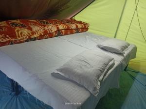 a bed in a tent with pillows on it at Him valley huts and camping in Tehri-Garhwāl