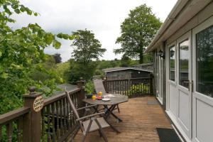 eine Terrasse mit Tisch und Stühlen auf einem Deck in der Unterkunft Comfortable 2 Bed Chalet near Snowdonia - Pass the Keys in Caeathro
