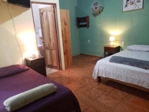 a bedroom with two beds and a mirror in it at Arenal Hostel La Catarata in Fortuna