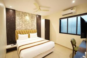 a bedroom with a bed and a desk and a window at Hotel Relax Residency in Mumbai