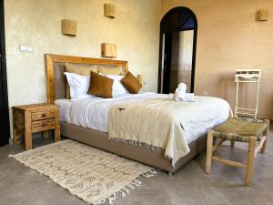 a bedroom with a bed and a chair and a mirror at Dar Mimosa in Essaouira
