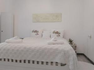 una camera bianca con un grande letto bianco con cuscini di In House a Tbilisi City