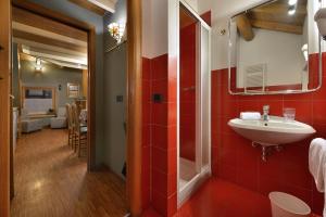 ein Badezimmer mit Waschbecken und rot gefliester Wand in der Unterkunft Cronox Mini Apartments in Livigno