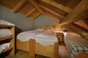 1 Schlafzimmer mit 2 Einzelbetten und Holzdecken in der Unterkunft Cronox Mini Apartments in Livigno