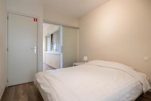 a bedroom with a white bed and a sliding door at BEL AIR HOLIDAY - Luxury 2-bedroom apartment with sea view & jacuzzi T48 in Ostend +7 photos