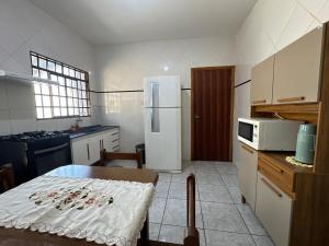 a kitchen with a table and a white refrigerator at Casa completa, ar e vaga, perto parque Ecológico in Ourinhos