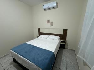 a small bedroom with a bed with a blue blanket at Casa completa, ar e vaga, perto parque Ecológico in Ourinhos
