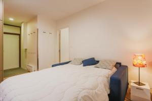 a large white bed in a room with a lamp at L HELIOS Centre ville 1 chambre in Cauterets
