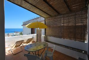 a patio with a table and chairs and a yellow umbrella at Zenzero canneto beach lipari in Canneto - Lipari
