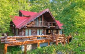 a log cabin in the woods with a red roof at Hakuba Loghouse in Hakuba