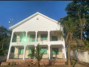 ein weißes Haus mit grünen Fenstern und einer Palme in der Unterkunft White House -Two palms in Kampala