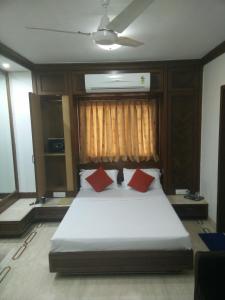 a bedroom with a bed with two red pillows at Strand Hotel, Colaba in Mumbai