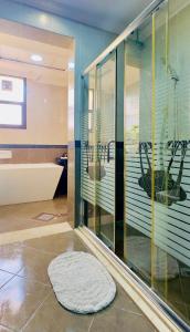 a bathroom with a tub and a glass shower stall at Mid-Century Modern Comfort 1BR in Abu Dhabi