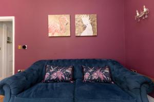a blue couch in a living room with three paintings at Luxury 2 Bedroom Georgian home, garden, Beach access, 6 guests in Bognor Regis +27 photos