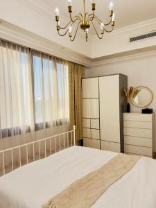 a bedroom with a bed and a chandelier at Mid-Century Modern Comfort 1BR in Abu Dhabi