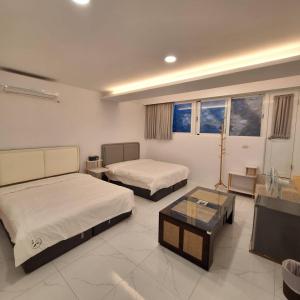 a bedroom with two beds and a table and a tv at 南灣沐洋168民宿 in Hengchun +5 photos