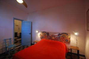a bedroom with a red bed and a blue door at Cannella studio flat Canneto Lipari in Canneto - Lipari