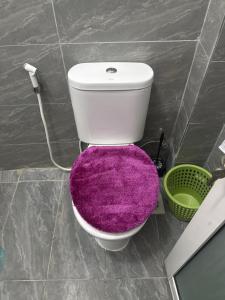eine weiße Toilette mit einem lila Teppich darauf in der Unterkunft PR Home Mtwapa Pride Apartments in Mombasa + 5 Fotos