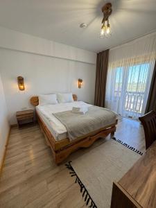a bedroom with a large bed and a large window at Pensiunea Roua Brazilor Mărișel in Mărişel