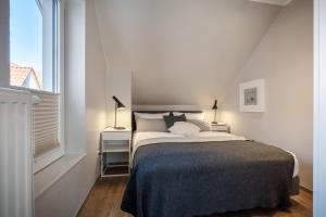 a white bedroom with a bed and a window at Wittehuus Wohnung 3 in Borkum +10 photos