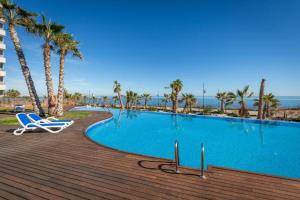 a swimming pool with two chairs and palm trees at Posidonia I MED by ZANIS in Punta Prima