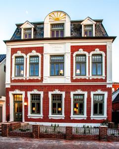 een rood bakstenen gebouw met veel ramen in een straat bij Logierhaus K15 Appartement 6 in Borkum +3 foto's