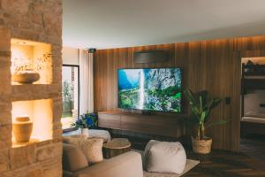 ein Wohnzimmer mit einem Fernseher an einer Holzwand in der Unterkunft Residence Alpi - Private Spa & Living in Grainau