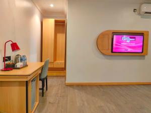a room with a desk and a tv on a wall at Ivy Hotel Aromire in Hausa