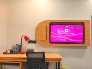 a flat screen tv hanging on a wall with a desk at Ivy Hotel Aromire in Hausa
