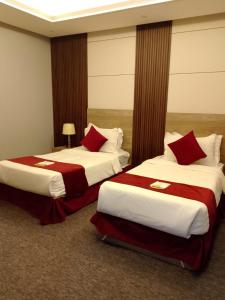 Dos camas en una habitación de hotel con almohadas rojas. en راحتي هنا 7, en Riad 12 fotos más