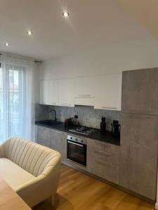 a kitchen with white cabinets and a couch in it at White Swan Apartment in Peschiera del Garda