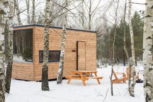 a small wooden cabin in the woods with a picnic table at УЛІС Кебіни in Dudky