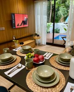 a table with plates and bowls of fruit on it at Breezia Villa Mezzanine with Private Pool in Blimbing