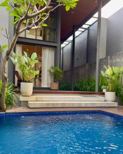a pool in front of a house with plants at Breezia Villa Mezzanine with Private Pool in Blimbing