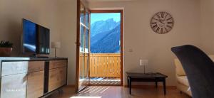 a living room with a television and a clock on the wall at Apartment Weber in Nova Levante