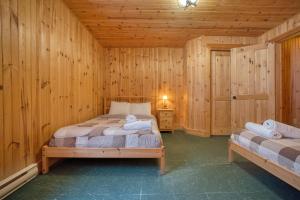 a bedroom with two beds in a wooden room at Chalet Cerf for 16 Guests, 7 min to SPA, Skiing in Saint-Paul-de-Montminy