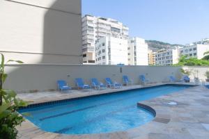a swimming pool with blue chairs in a building at Studio Corcovado in Rio de Janeiro
