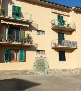 Un edificio con ventanas verdes y un cartel delante. en Giulia House, en Certaldo