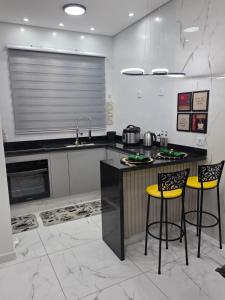 une cuisine avec deux tabourets de bar jaunes et un comptoir dans l'établissement Apartamento Moderno Paraquesdismo e Balão, à Boituva
