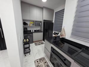 une cuisine avec des armoires blanches et un réfrigérateur noir dans l'établissement Apartamento Moderno Paraquesdismo e Balão, à Boituva