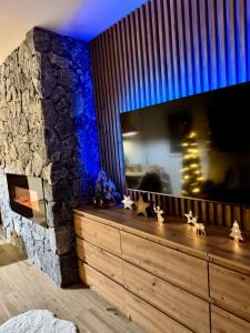 a living room with a tv and a stone wall at Kamzík 51 Donovaly in Donovaly