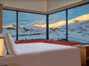 a bedroom with a view of a snowy mountain through a window at Hilton Altay Hemu in K'u-mu