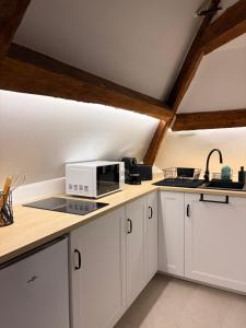 a kitchen with white cabinets and a microwave at Suite Spa Cinta in Trie-Château