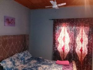 Cutting Edge Guest House في Daranka: غرفة نوم بها سرير ونافذة بها مروحة +27 صورة