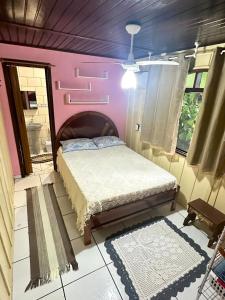 a bedroom with a bed and a pink wall at Kitinete da Cris in Ilha do Mel